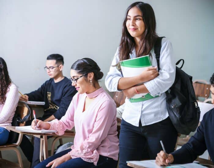 woman carrying white and green textbook