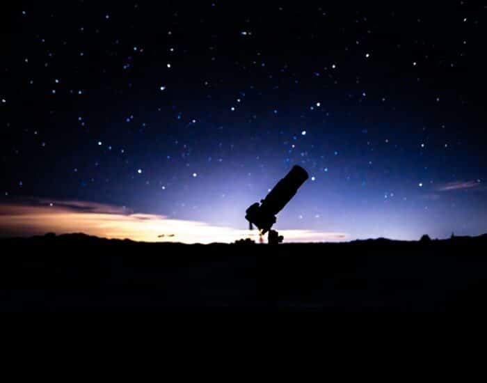 a telescope sitting on top of a hill under a night sky