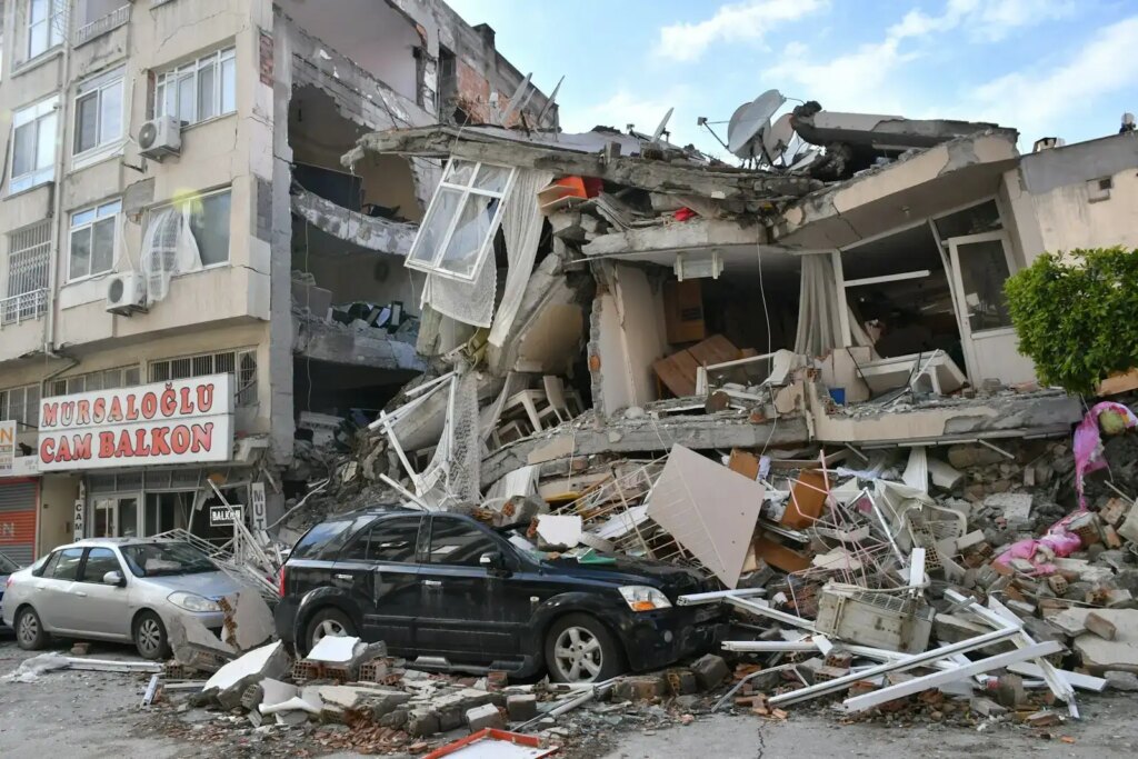 Causas dos terremotos e como eles ocorrem 1 a car is parked in front of a destroyed building